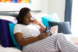 Vrouw op de bank die op haar telefoon kijkt